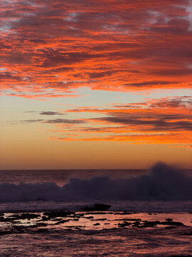 Fiery red and orange clouds sweep across the evening sky above a distant horizon, creating a vivid atmospheric landscape perfect for travel, nature and dramatic background designs.