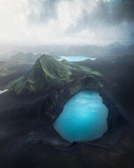 Brilliant turquoise crater lake sits among dramatic volcanic peaks beneath misty clouds, creating a spectacular wilderness landscape ideal for geology, tourism and adventure travel. © UQink