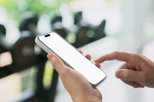 Person using smartphone with blank screen at gym.