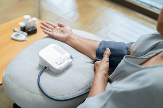 Elderly woman using measuring her blood pressure with a digital monitor, personal wellness, health monitoring.