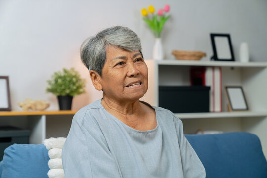Portrait of an elderly Asian woman relaxing on a couch in her living room at home.