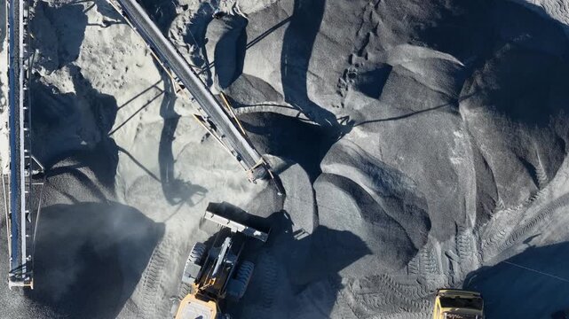 Aerial view of a bulldozer loading coal into a truck at a large industrial mine in Indonesia