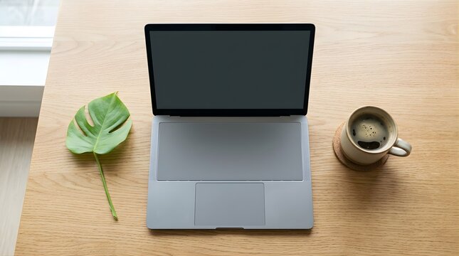 Laptop on wooden desk with coffee and leaf for creative workspace mockup