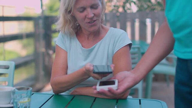 Contactless payment made by a mature woman at a cafe