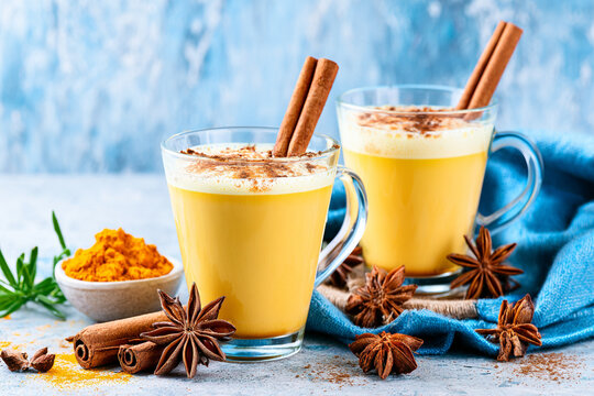 Golden turmeric milk latte in glass mugs with cinnamon sticks and star anise