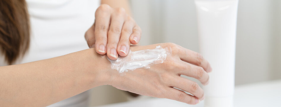 Health skin care, beauty smile asian young woman, girl  hand applying, putting moisturizer on her arm, shoulder after shower bath at home. Skin body cream moisturizing lotion, routine in the morning.