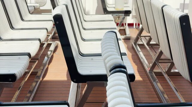 White boat seats stand in neat rows on a wooden deck in Saint Petersburg. The empty chairs offer a peaceful and calm feeling for tourists during a river cruise.
