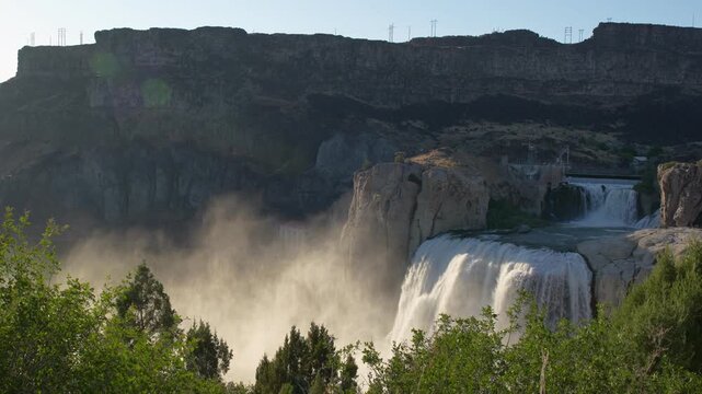 View of Shoshone Falls cascading over rocky cliffs with lush green foliage in Twin Falls County, Idaho, United States.
