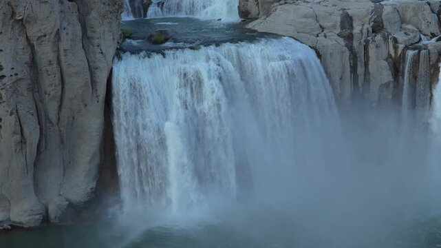 View of Shoshone Falls cascading over rugged cliffs with mist rising from the river below in Twin Falls County, Idaho, United States.