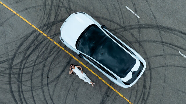 Top view of white ev car.
New ev car on tire marks.
Fast ev car parked on road.