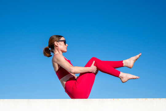 Woman Performing Core Exercises Against Blue Sky