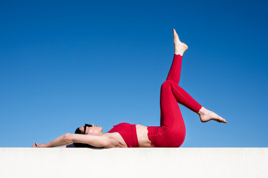 Woman Performing Advanced Yoga Pose Against Blue Sky