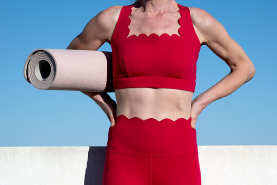 Fitness Woman Holding Yoga Mat Against Blue Sky