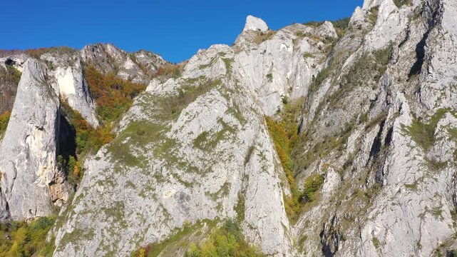 Aerial rocky alpine mountain landscape, white limestone cliffs autumn forest by drone