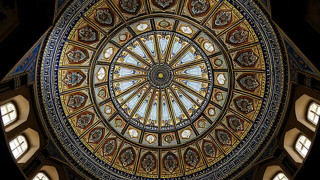 Intricate geometric tilework inside a mosque dome in gold and blue.