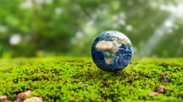 Miniature Earth globe resting on vibrant green moss surrounded by lush vegetation, representing nature, environmental protection, sustainability, ecology, and care for the planet.