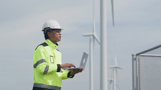 Engineer and technician inspecting wind turbine equipment with laptop, wearing safety gear and helmet renewable energy facility for industrial maintenance, safety inspection, and clean power