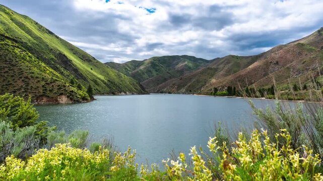 View of Lucky Peak Lake with rolling mountains and lush vegetation under a cloudy sky in Ada County, Idaho, United States.
