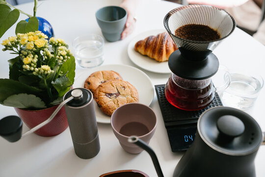 Bright Home Coffee Moment with Fresh V60 Pour Over Brewing Beside a Croissant and Cookies on a Cozy Breakfast Table with Flowers