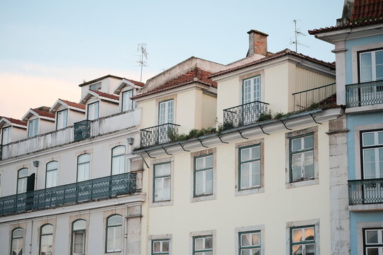 Traditional residential buildings near Rossio railway station, featuring tiled roofs, dormer windows, wrought-iron balconies and visibly aged fa&ccedil;ades characteristic of central Lisbon.