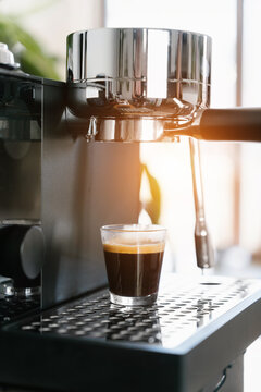 Fresh Espresso in Glass Cup on Professional Coffee Machine with Warm Morning Sunlight