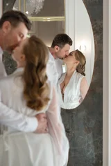 Happy wedding couple embracing and smiling at their reflection in a mirror. Elegant indoor portrait capturing love, connection, and joyful newlywed moments. © Khorzhevska