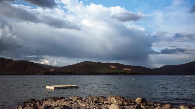 View of Lucky Peak Lake with a floating dock on the water, distant hills, and a cloudy sky in Ada County, Idaho, United States.