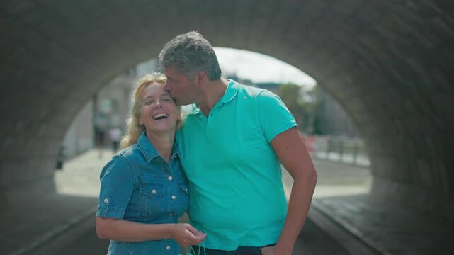 Sharing a kiss while walking beneath a city bridge