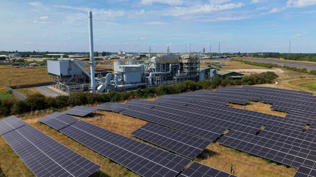 Aerial view of biomass energy recovery power plant and solar panel array in rural UK