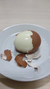 Peeled boiled egg with cracked eggshell on white plate