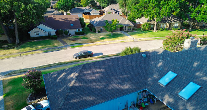 Charcoal sedans line curbed Mockingbird Lane pavement within classic DFW suburbs. Sunlit shingle rooflines peek above leafy tree canopies across Coppell, Texas