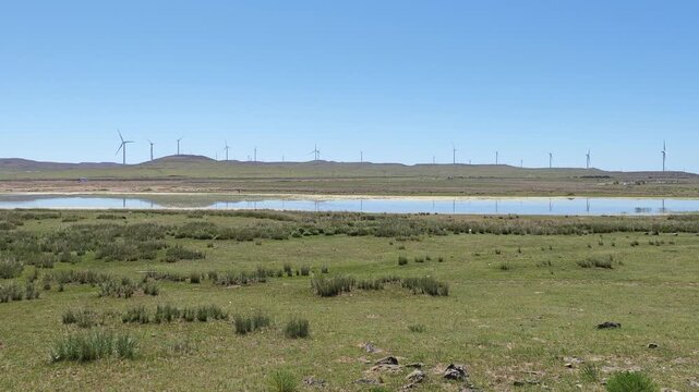 Scenic landscape of salt lake wetland and distant wind turbines in summer in Ulan Hada Volcano Geopark, Ulanqab, Inner Mongolia, China