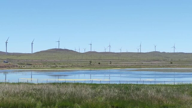 Scenic landscape of salt lake wetland and distant wind turbines in summer in Ulan Hada Volcano Geopark, Ulanqab, Inner Mongolia, China