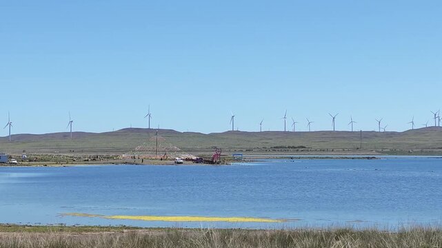 Scenic landscape of salt lake wetland and distant wind turbines in summer in Ulan Hada Volcano Geopark, Ulanqab, Inner Mongolia, China