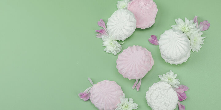 Fruit marshmallow with fresh flower petals on pastel green background. Lactose free vegan dessert