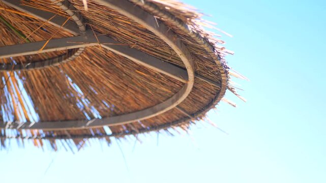 Extreme Close Up Of A Rustic Thatched Beach Umbrella Against A Clear Blue Sky. Detailed Natural Straw Texture And Warm Sunlight Create A Premium Summer Travel Scene.