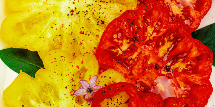 Carpaccio, assorted slices of red and yellow heirloom beefsteak tomatoes seasoned, spices, olive oil