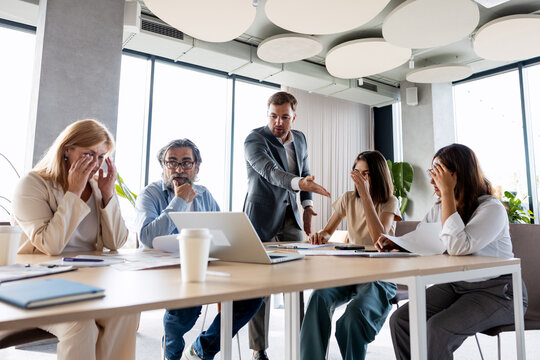 Boss yelling at upset employees during office meeting