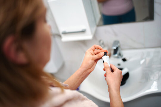 Woman applying skincare product in bathroom routine