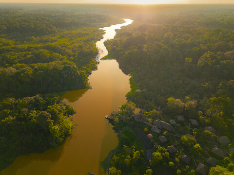 Aerial view of winding river in the dense Amazon rainforest during golden hour, El Retiro, Sucumbios, Ecuador.