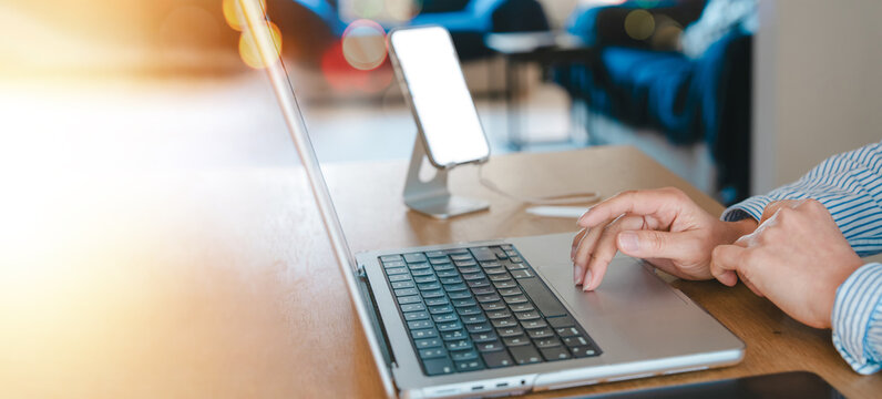 Business Woman Typing On Laptop With Smartphone In Living Room, Working Online As Customer Service Adviser, Middle Aged Professional Using Technology In Remote Home Office And Hybrid Workplace.