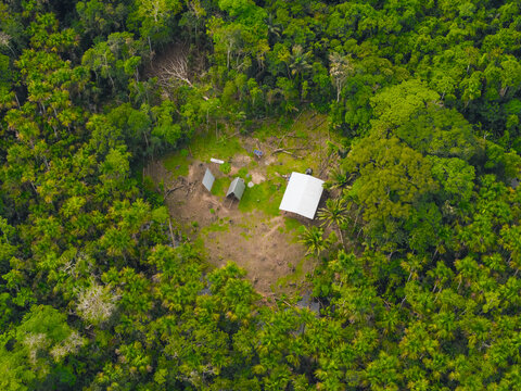 Aerial view of lodge nestled in a clearing within the dense Amazon rainforest, featuring a white-roofed structure surrounded by lush green trees in El Retiro, Sucumbios, Ecuador.