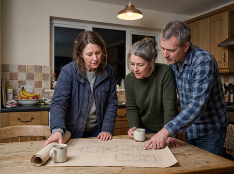 Adult daughter going through documents at the kitchen table with her senior parents, family finances and later life planning