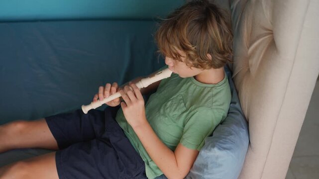 A little boy learns to play the flute at home, practicing with focus and enthusiasm in a cozy, warm setting. A charming scene of early musical exploration, creativity, and childhood growth.