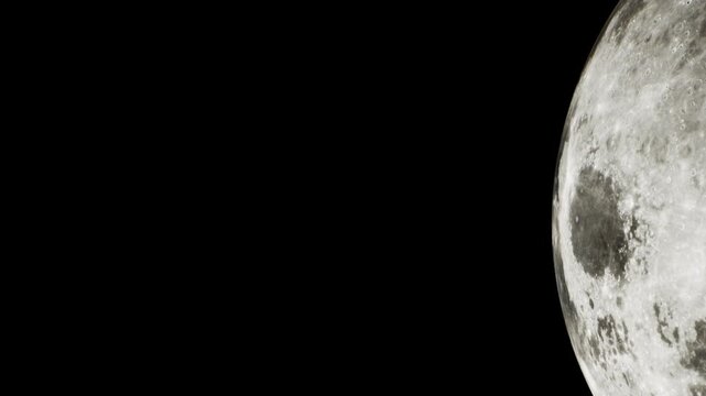 A large moon appears against a dark sky. The surface shows craters and details clearly. The scene captures the brightness of the moon during nighttime with a clear view.