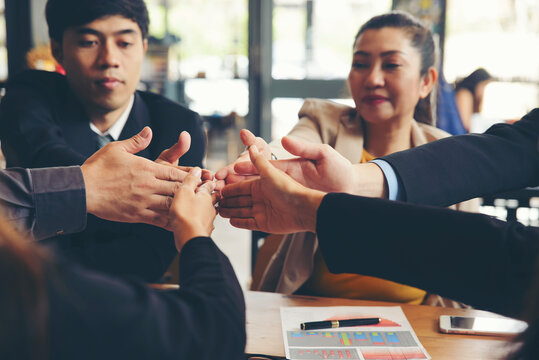 Group of businesspeople celebrating successful deal with team, showing thumbs-up gestures and teamwork during business meeting, with happy corporate employees working together.