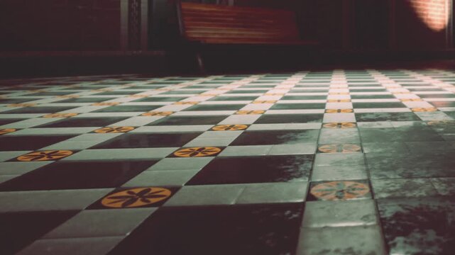 A close view of a floor with black and white tiles and yellow flower patterns. The area has a wooden bench nearby. The lighting appears low and creates shadows.