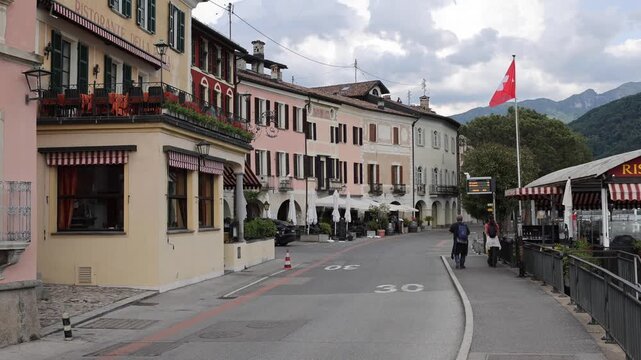 Morcote, Switzerland - 21 August 2026: View of the picturesque street in Morcote with historic buildings, restaurants, and pedestrians walking along the waterfront.