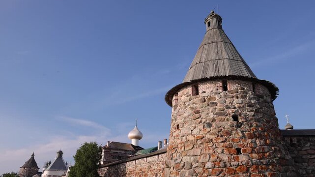 Solovetsky, Arkhangelsk Oblast, Russia - 20 August 2026: View of the historic stone walls and towers of the Solovetsky Monastery with tourists walking along the path.