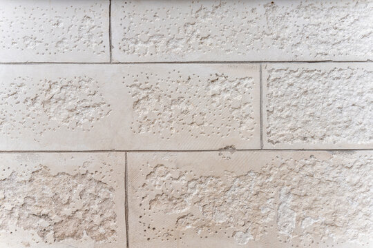 Rough texture of porous light limestone brick wall masonry, architectural building facade background.